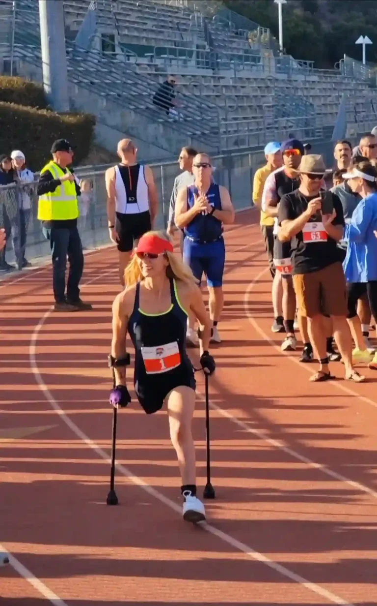 An athlete using crutches runs on a track surrounded by cheering spectators, showcasing determination and athleticism.