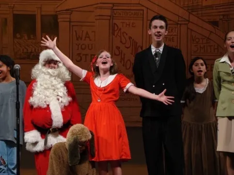 Young performers in period costumes, including Santa Claus.