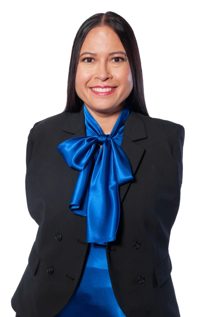 A professional headshot of Jessica Cox, a woman born without arms, smiling at the camera while wearing a black blazer with a bright blue scarf tied in a bow.