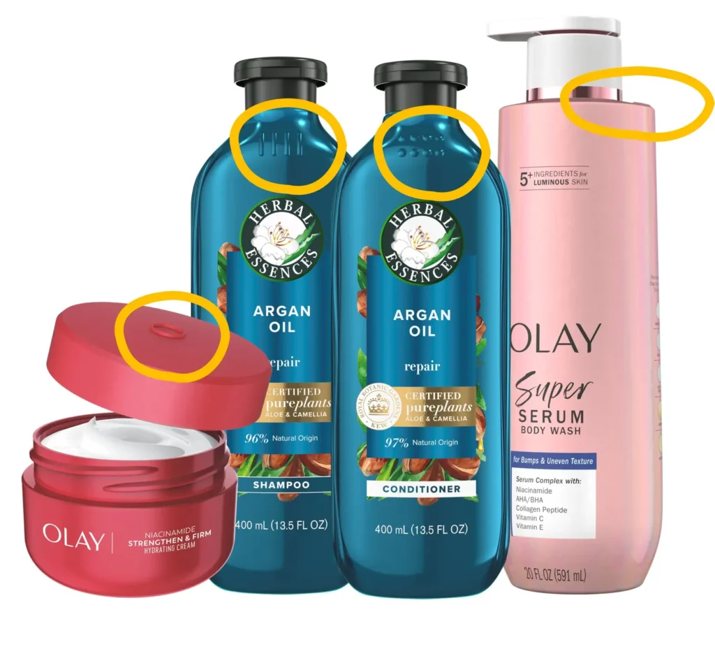 A collection of Olay and Herbal Essences personal care products including shampoo, conditioner, body wash, and face cream. Yellow circles highlight the tactile markers on the bottles and lids, such as raised lines and dots, designed for identification by touch.