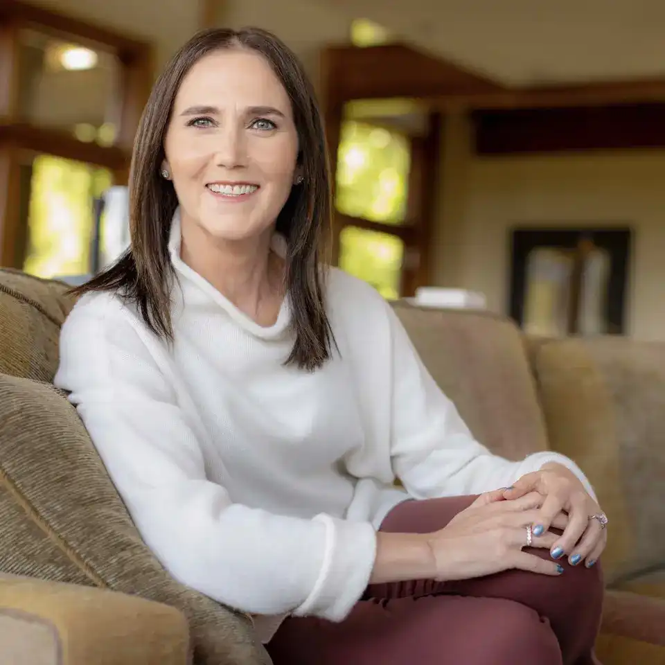 Portrait of hearing health advocate Shari Eberts sitting casually on a sofa and smiling at the camera.