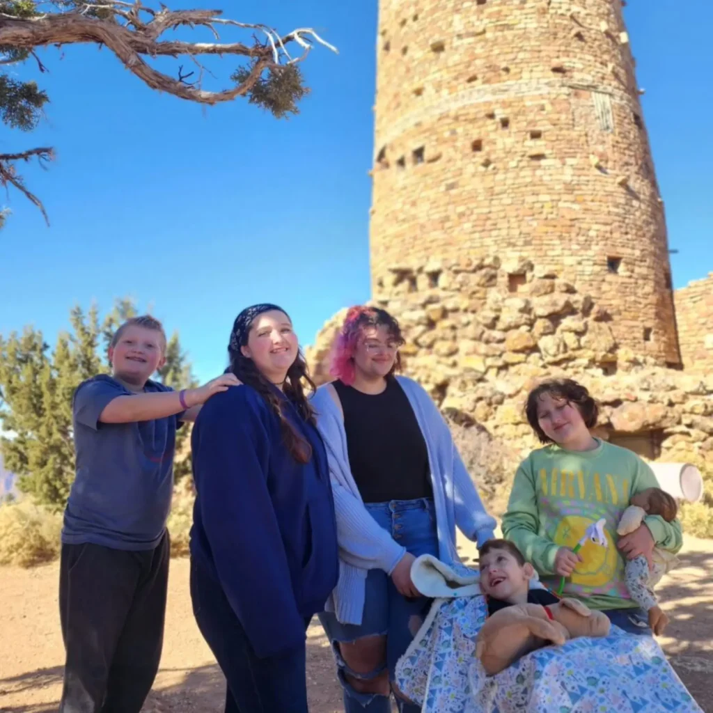 Family gathered outside with the stone Desert View Watchtower standing tall in the background at the Grand Canyon.