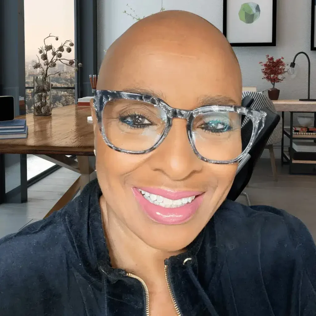 Close-up portrait of Mary Johnson wearing glittery grey eyeglasses in a modern home office.